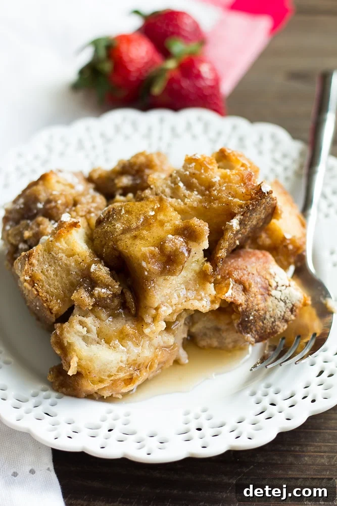 Ultimate Vegan French Toast Bake 6 A single, generous slice of vegan French toast casserole on a white plate, with a fork poised to take a bite, emphasizing its readiness to be enjoyed.