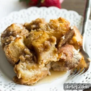 Ultimate Vegan French Toast Bake 7 A single, generous slice of vegan French toast casserole on a white plate, with a fork poised to take a bite.