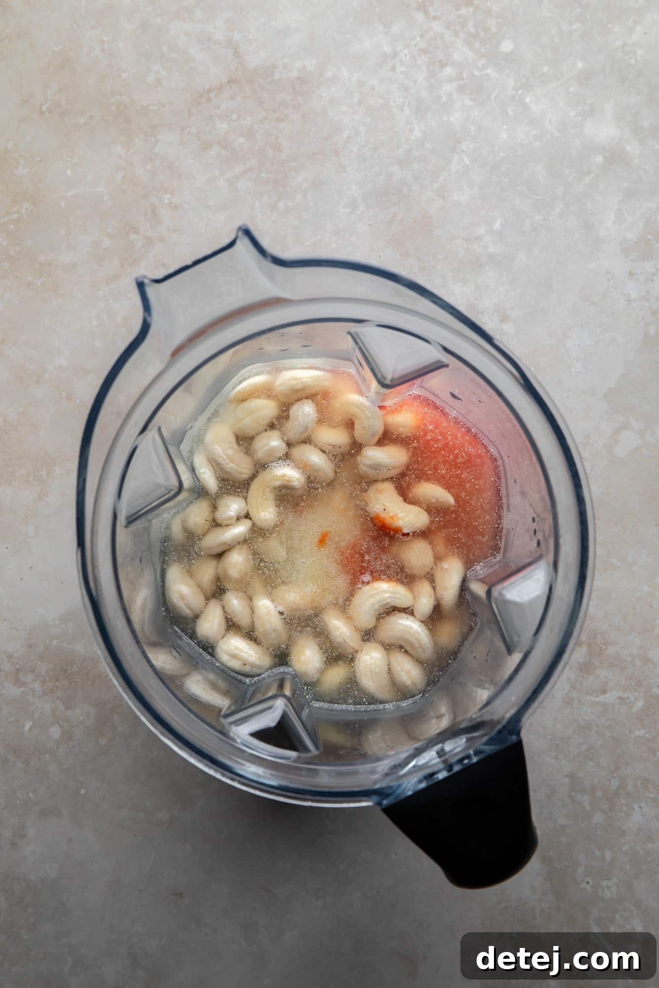 Ingredients for vegan buffalo chicken dip in a blender, showing cashews and spices.