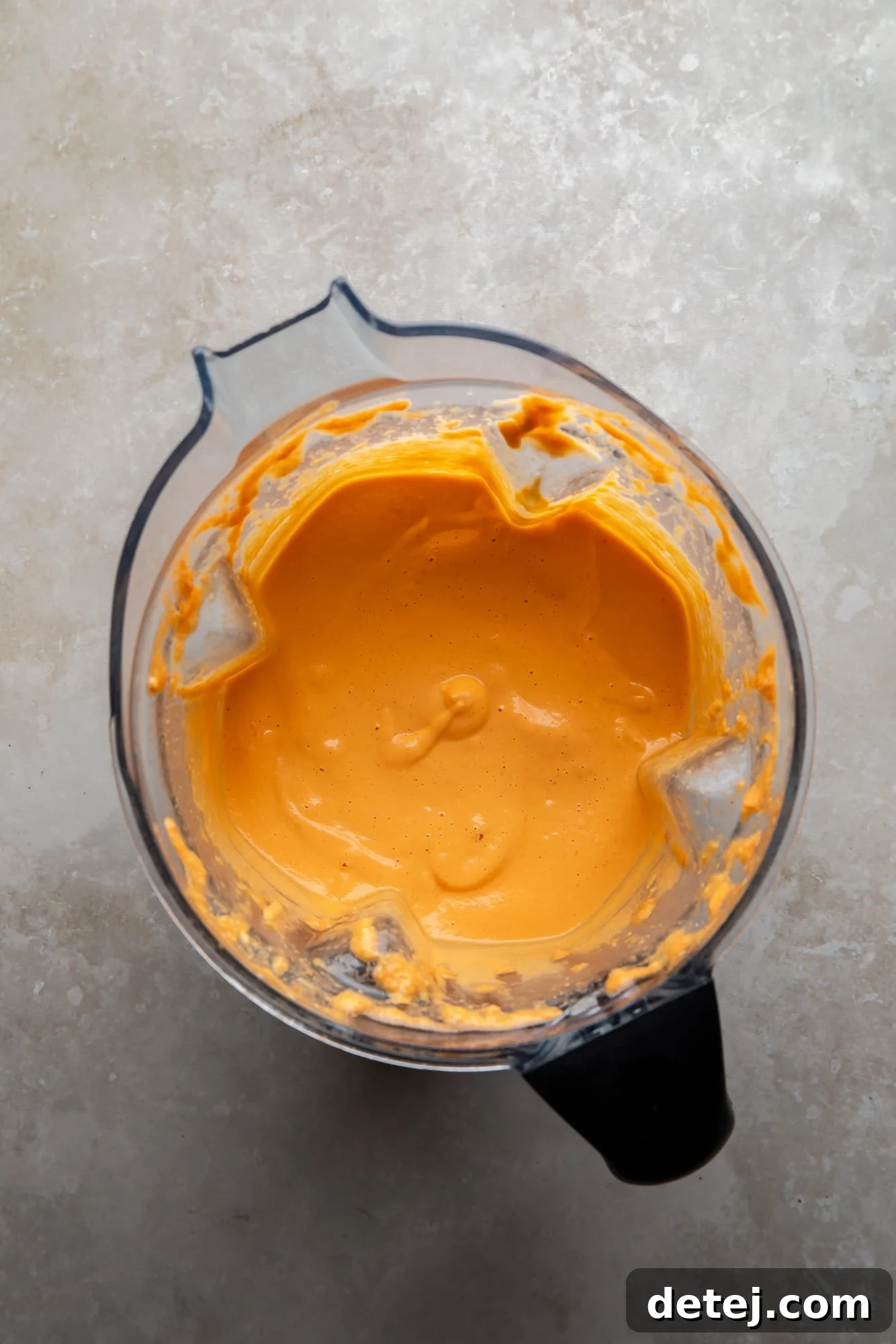 Smooth, blended orange vegan buffalo chicken dip base in a blender, ready for the next step.