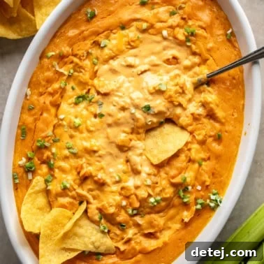 overhead view of vegan buffalo chicken dip in a large white baking dish surrounded by tortilla chips.