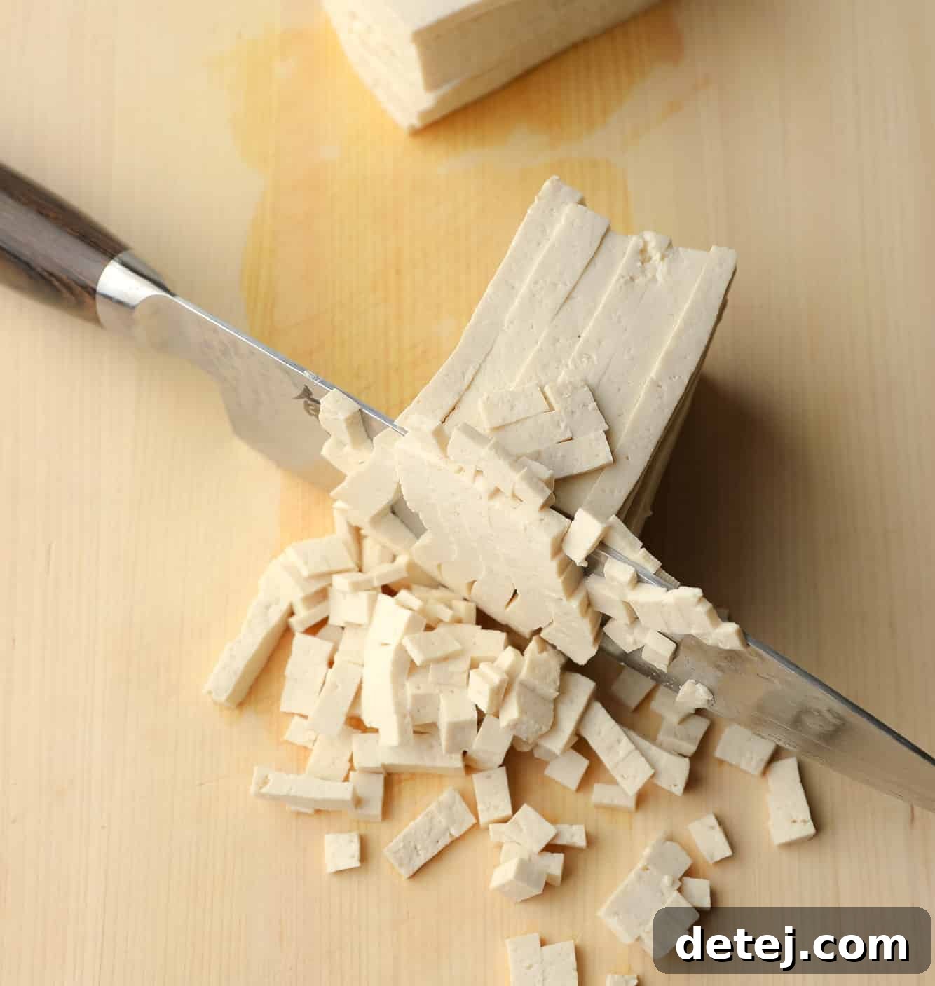 using a chef's knife to meticulously chop sliced tofu into very small squares, illustrating the technique for an authentic egg-like texture.