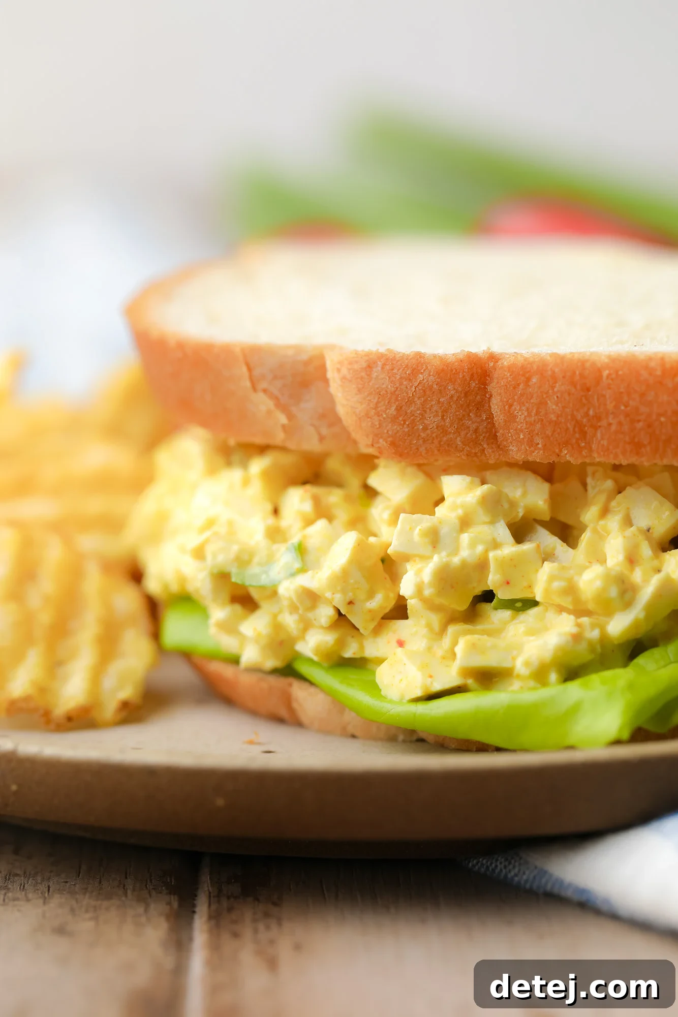 close up on a perfectly assembled vegan egg salad sandwich, highlighting the textures and vibrant colors of the filling.