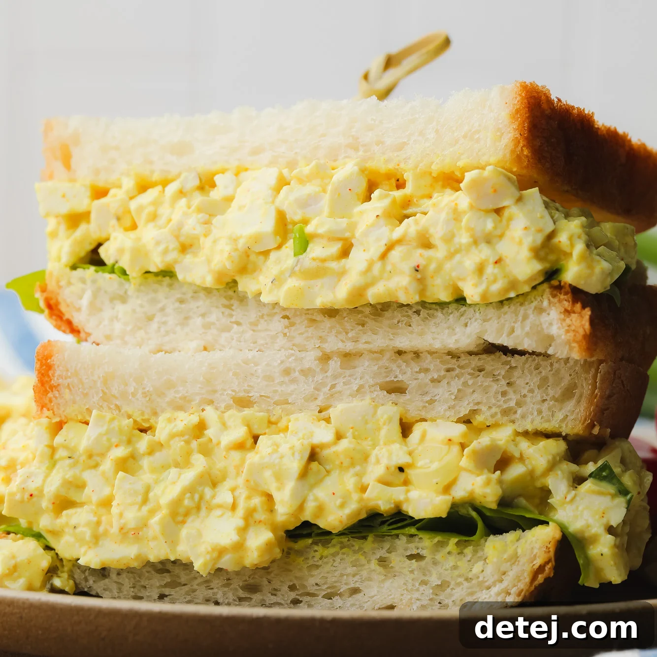 two vegan egg salad sandwiches piled on top of each other.