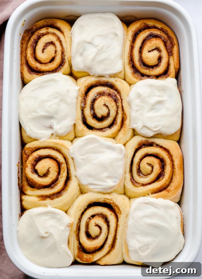 A dish filled with frosted vegan cinnamon rolls, showcasing their fluffy texture and generous icing.