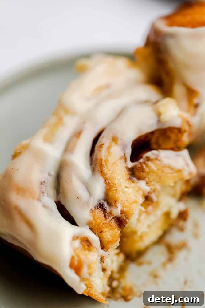 A broken vegan cinnamon roll on a grey plate, revealing its soft, gooey cinnamon-sugar interior.