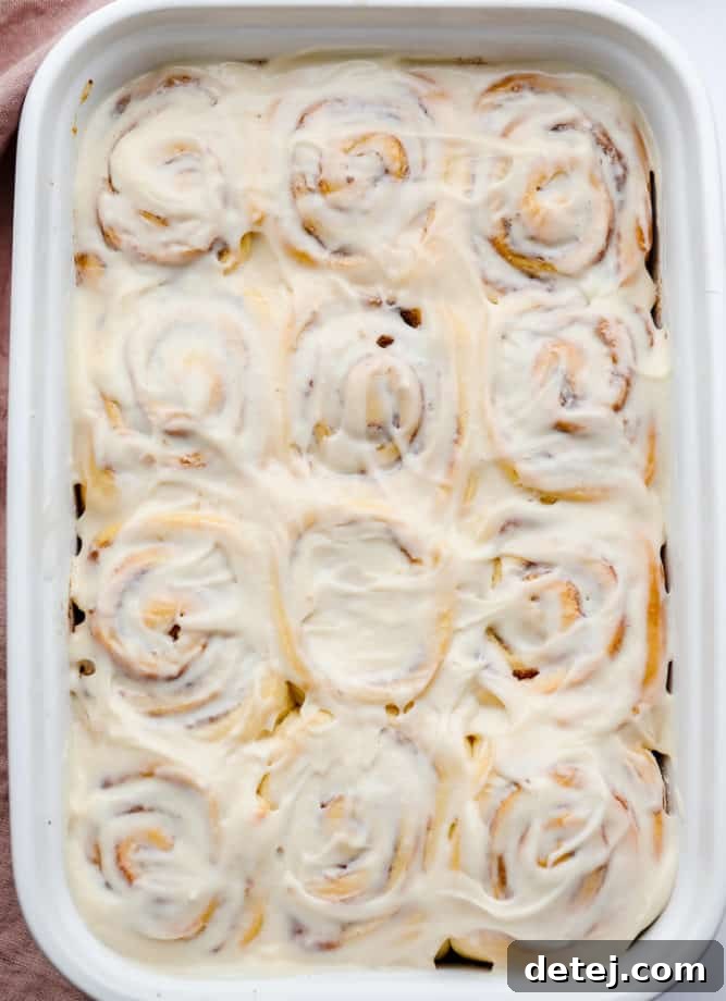 An overhead shot of a large plate brimming with generously frosted vegan cinnamon rolls.