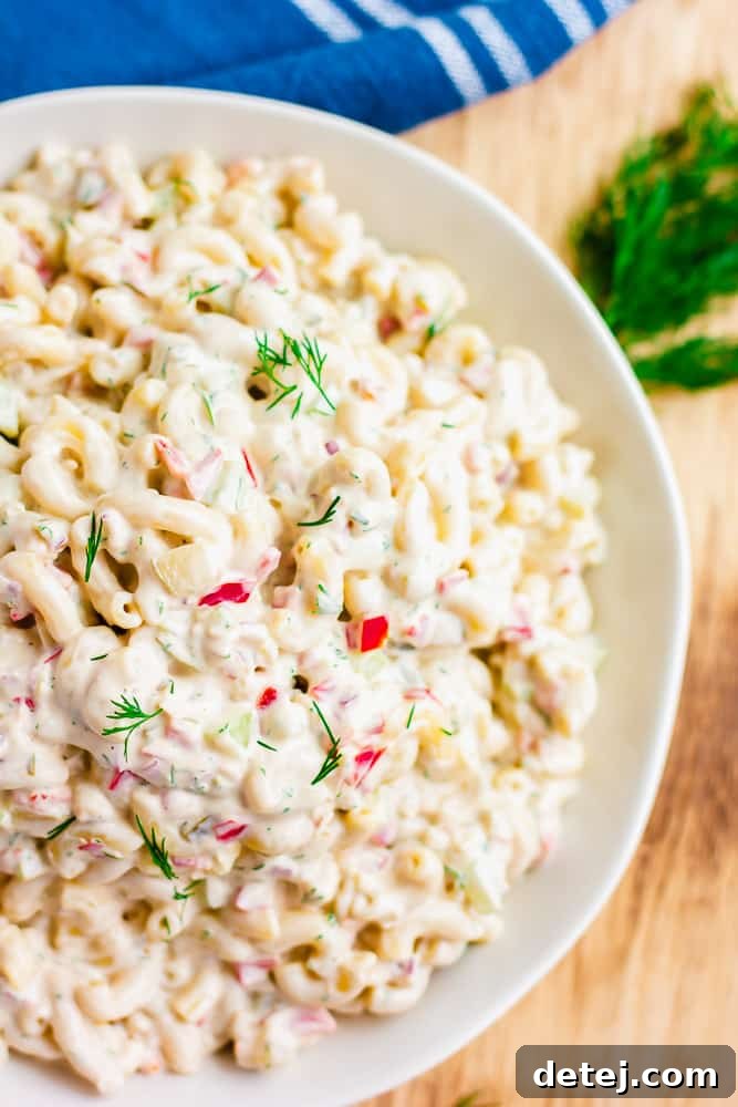 A beautifully presented large bowl of vegan macaroni salad, artfully placed on a rustic wooden background, inviting you to dig in.