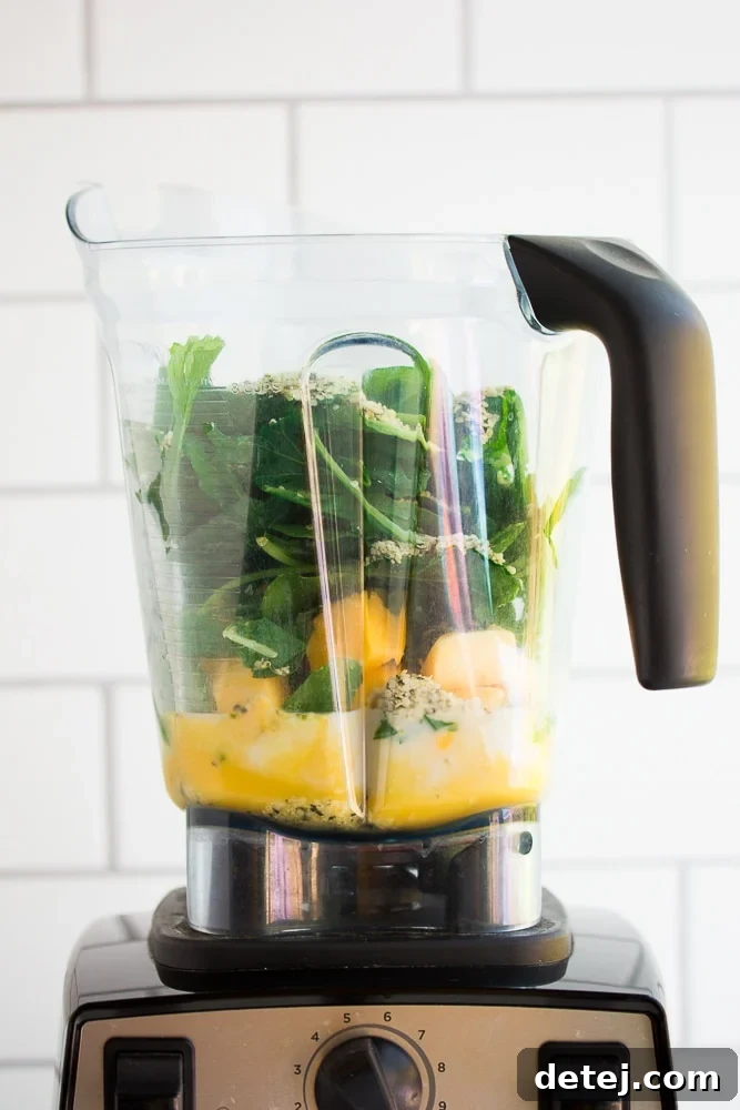 An unblended vegan green smoothie in a blender, showing all the fresh ingredients before blending.