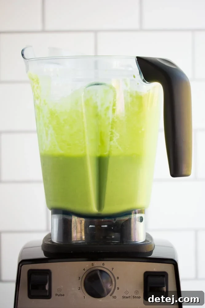 A high-powered blender filled with a perfectly blended, creamy vegan green smoothie, ready to be poured and enjoyed.