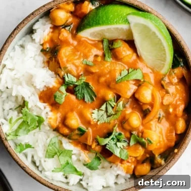 close up of a bowl with creamy tomato chickpeas, white rice and limes