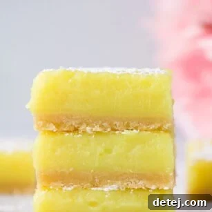 3 stacked vegan lemon bars with pink flowers in background