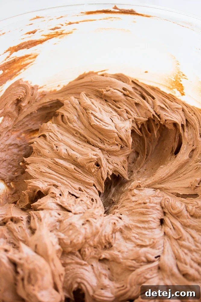 A large bowl filled with perfectly beaten vegan chocolate frosting, showcasing its smooth, airy, and rich texture, ready for use.