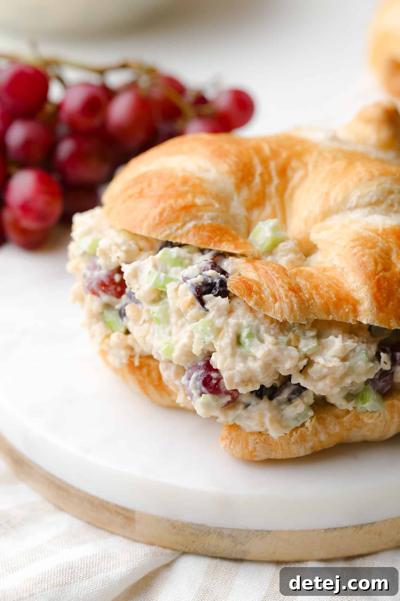 close up on vegan chicken salad in a croissant sandwich.