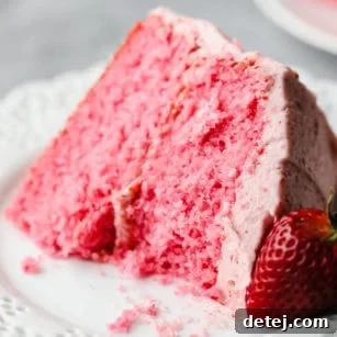 square image of a piece of pink cake with a strawberry on the side