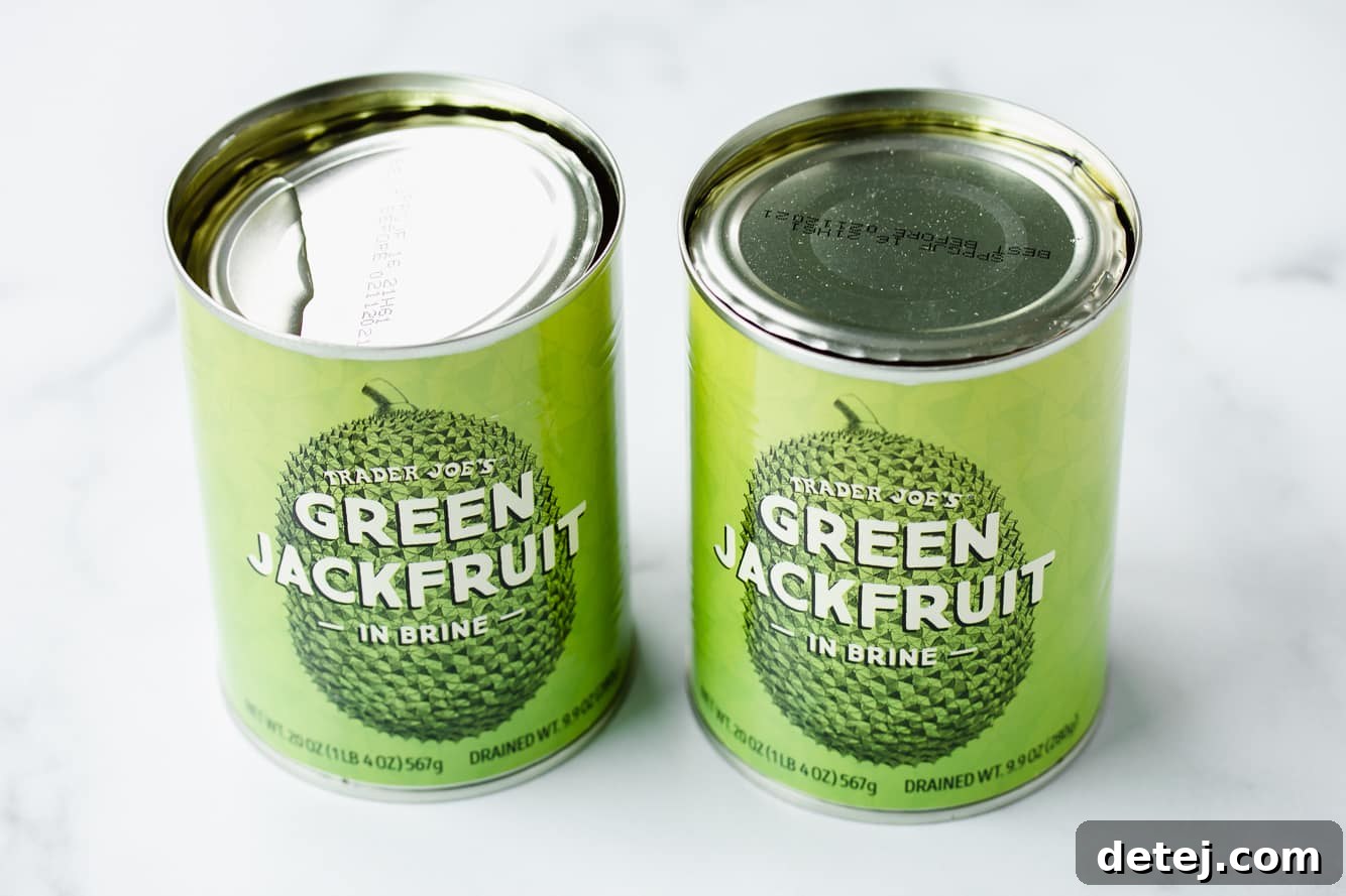 Two green cans of Trader Joe's young green jackfruit in brine, ready for preparing vegan pulled pork.