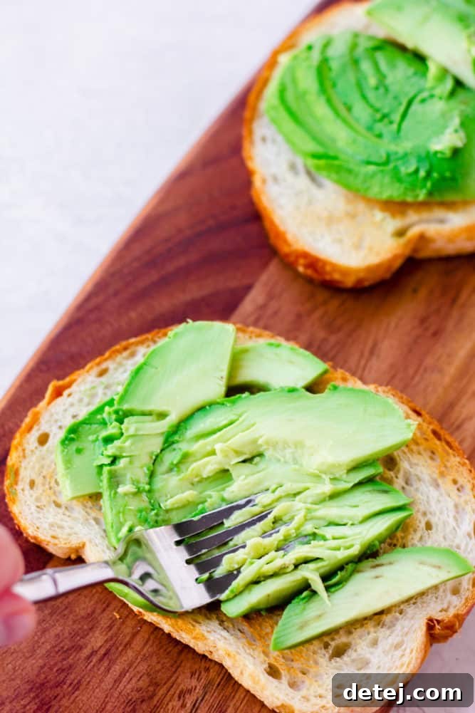 a fork mashing avocado on bread