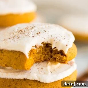 close up of a vegan pumpkin cookie with a bite taken out of one. Perfectly soft and frosted.