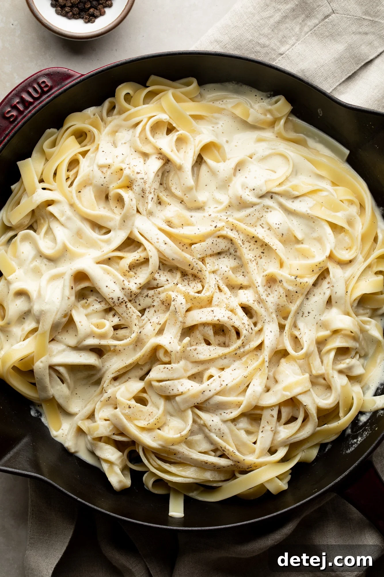 cast iron pan with white creamy sauce and pasta noodles