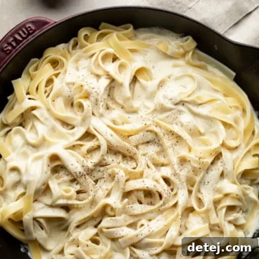 square image of fettuccine alfredo with black pepper in cast iron pan