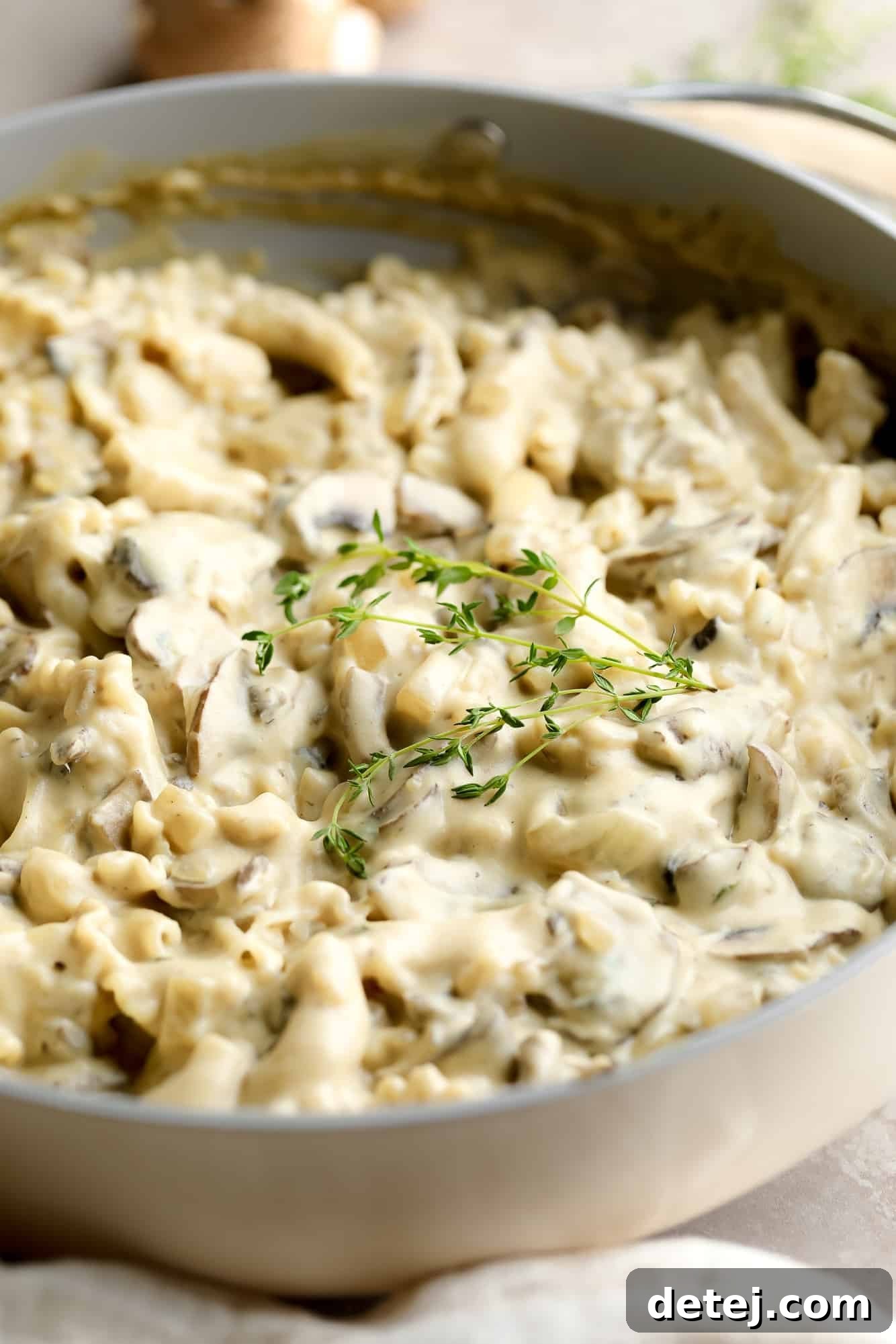 A large pot filled with creamy vegan mushroom stroganoff, garnished with fresh herbs, ready to be served.