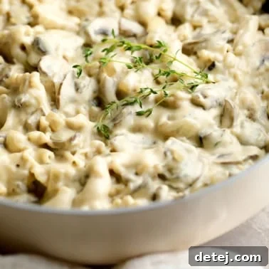 close up on vegan mushroom stroganoff topped with thyme in a pot.