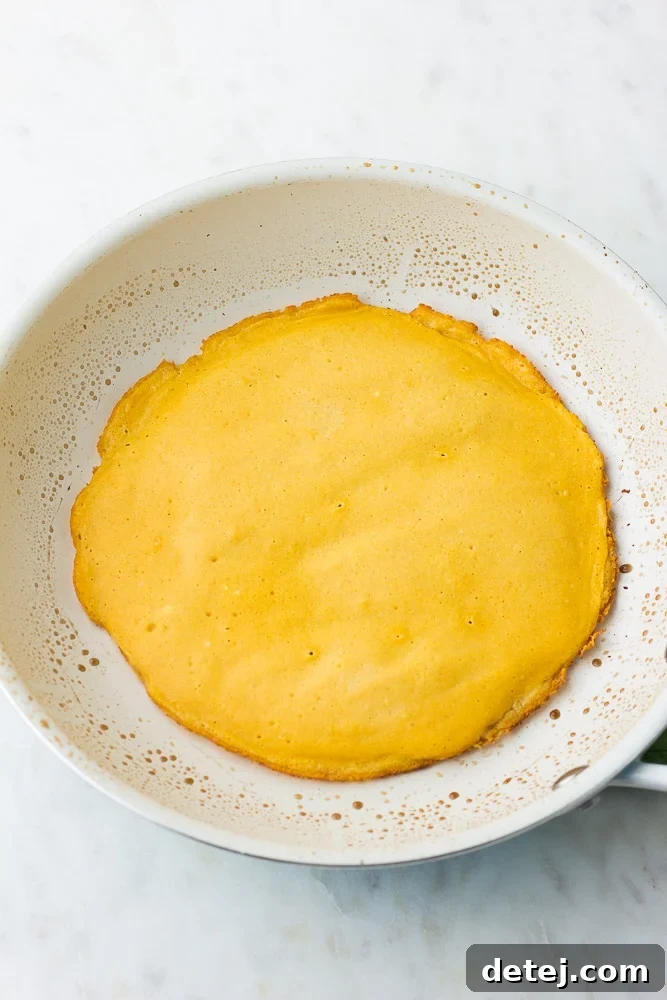 plain vegan omelette cooking in a white pan