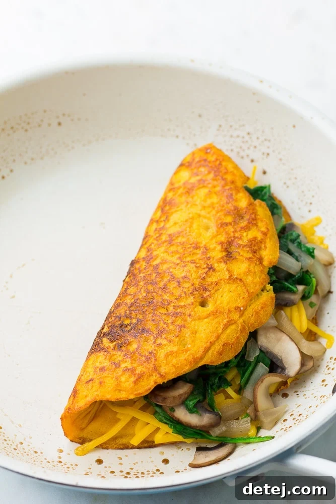omelette in white pan just flipped and stuffed with veggies
