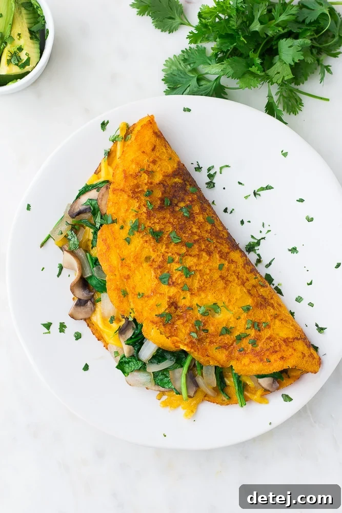 looking down on a vegan omelette on a white plate with cilantro all over it