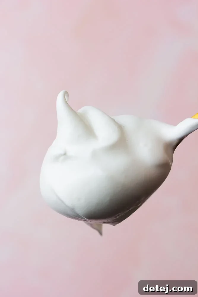 A golden spoon holds a generous scoop of light and fluffy vegan whipped cream, highlighting its airy texture.