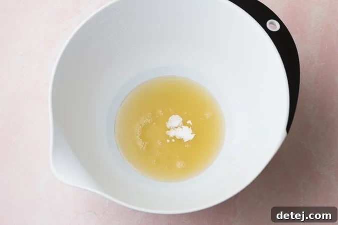 A white bowl containing chickpea liquid (aquafaba) and a small amount of cream of tartar, ready for whipping.