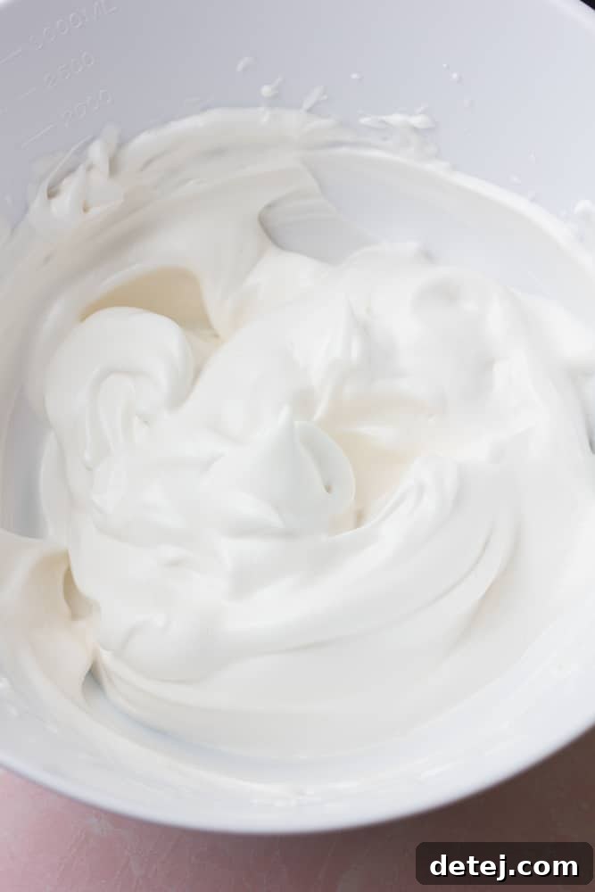 A pristine white bowl overflowing with beautifully fluffy and white vegan whipped cream, ready to be enjoyed.