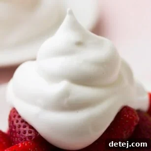 very close up shot of vegan whipped cream on a plate of strawberries with pink background