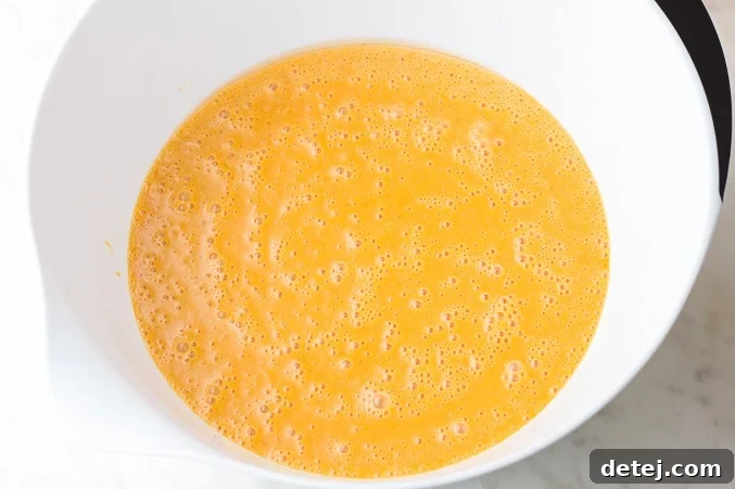 a bowl containing whisked wet ingredients for pumpkin waffles: pumpkin puree, oil, soy milk, and sugar
