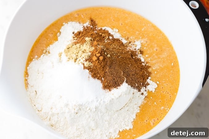 dry ingredients being added on top of wet ingredients in a bowl for vegan pumpkin waffles
