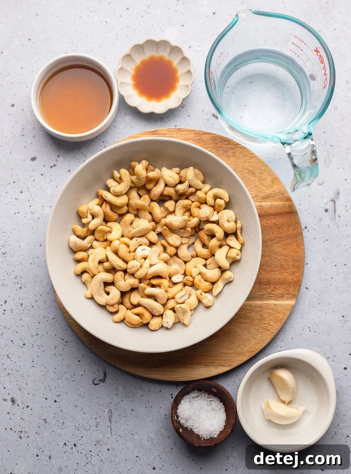 Individual bowls display the core ingredients for cashew cream: raw cashews and water, ready for blending.