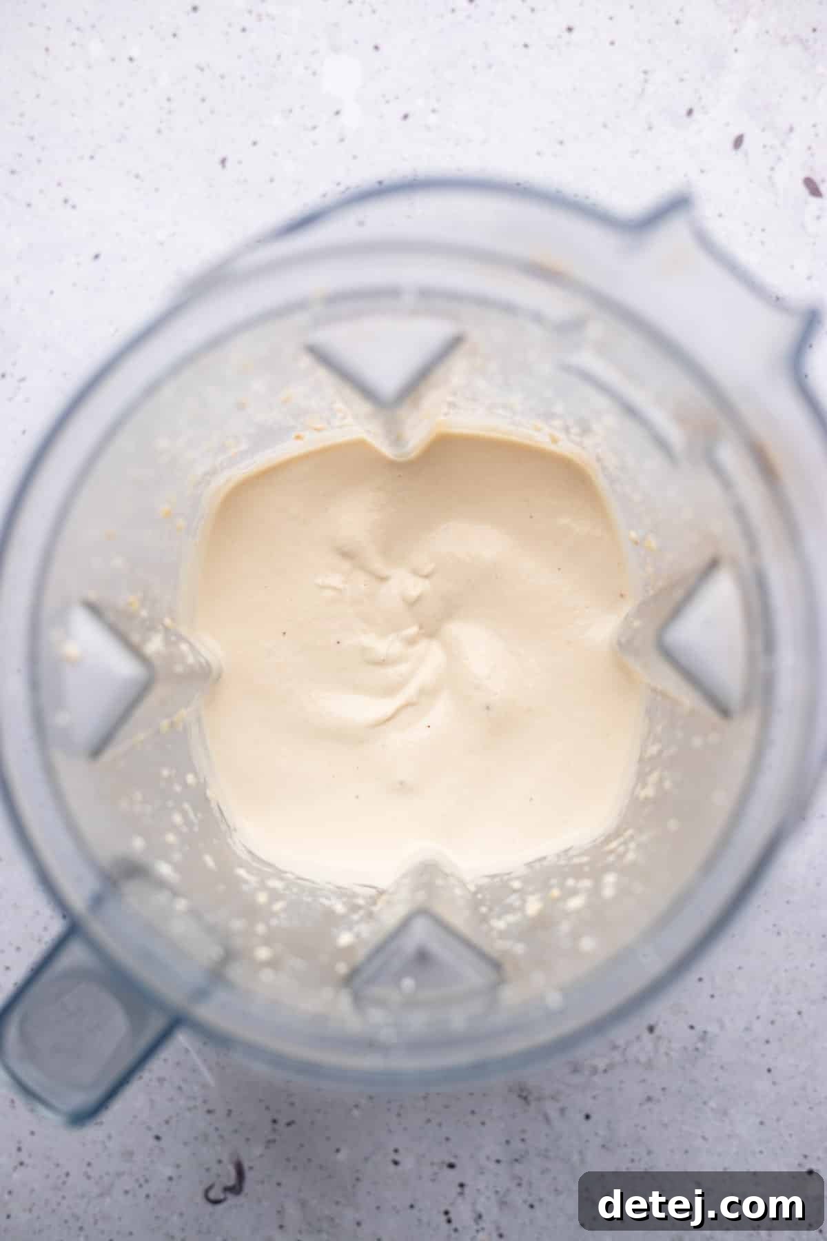 A high-powered blender filled with smooth, white cashew cream, showcasing its perfect, velvety texture.