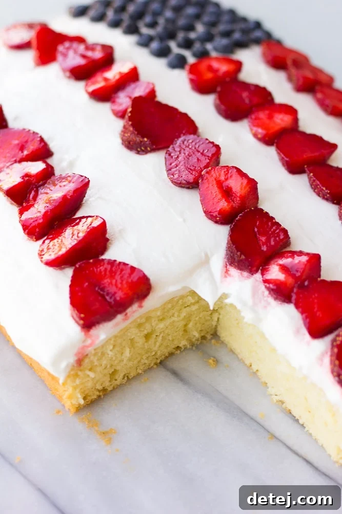 A slice of vegan flag cake, showing the fluffy cake, creamy frosting, and fresh berries inside.