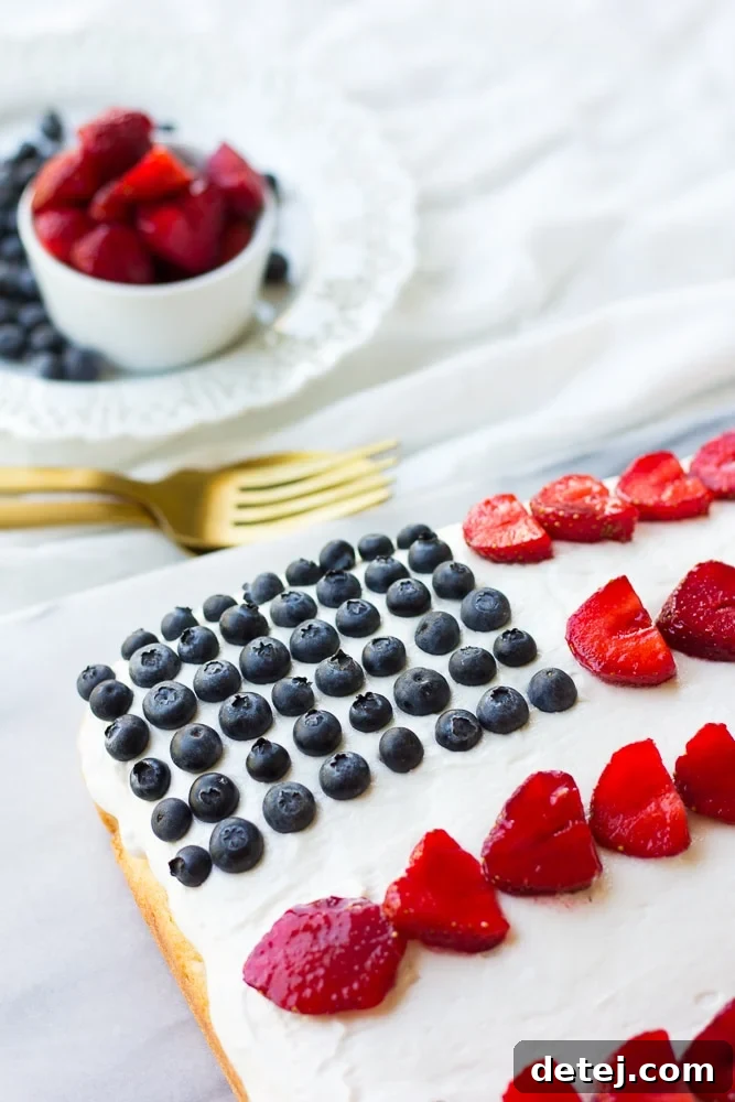 Top-down view of the vegan flag cake, highlighting the beautiful arrangement of red strawberries and blue blueberries on white frosting.