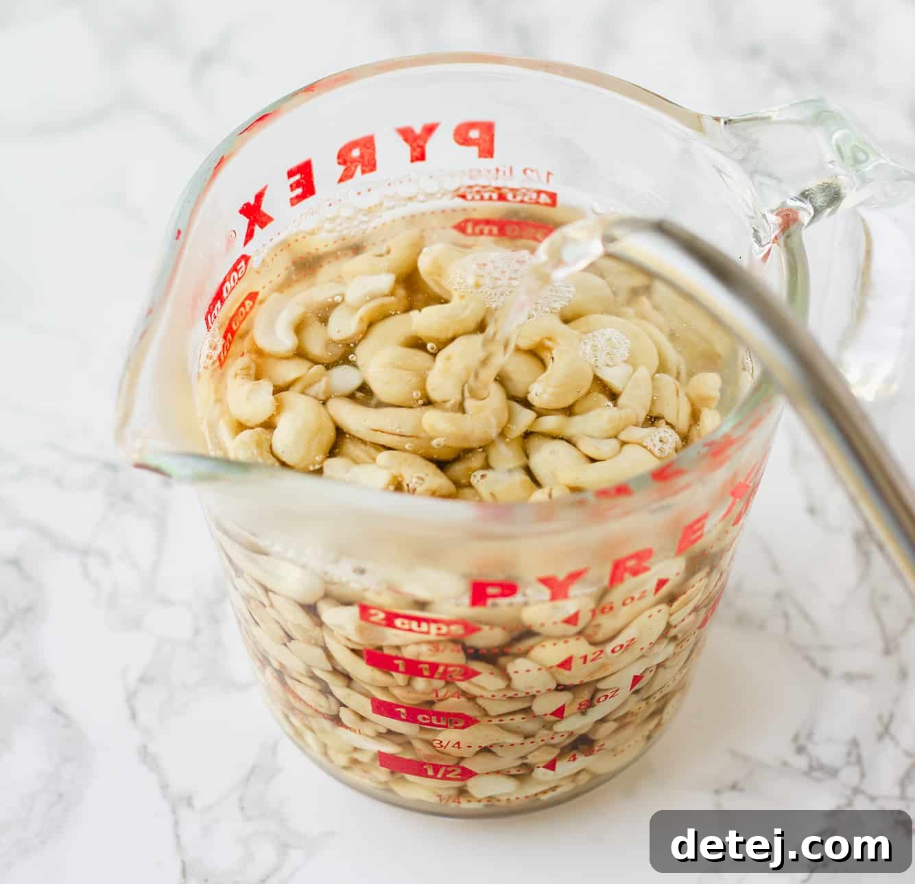 Vegan Ranch Dressing 3 soaking cashews in hot water in a large glass measuring cup.