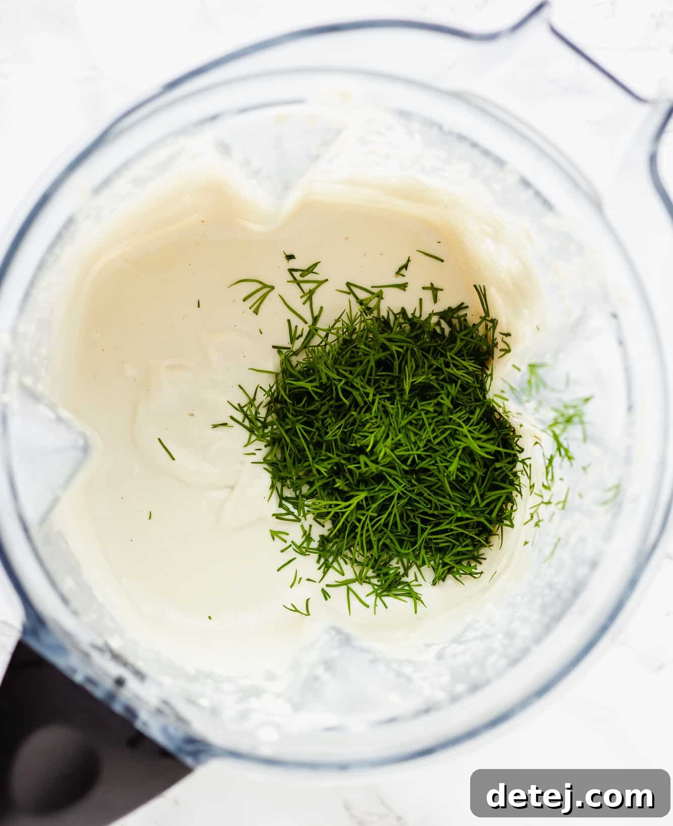 Vegan Ranch Dressing 4 fresh dill on top of a creamy white sauce in a blender.