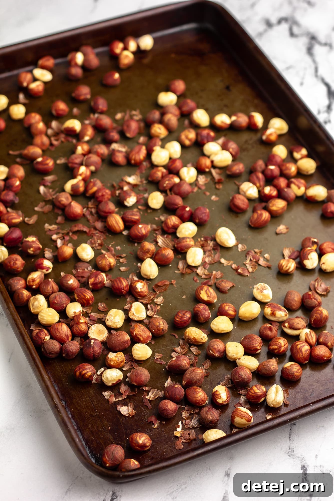 roasted hazelnuts on a metal baking sheet.