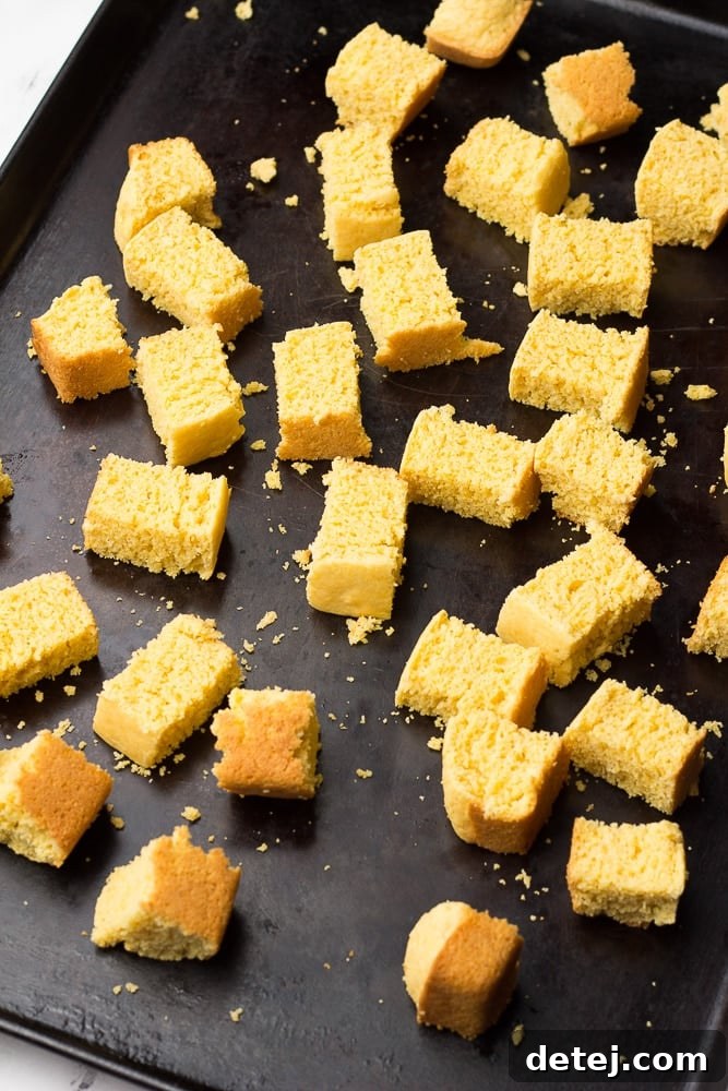 Close-up view of cubed vegan cornbread spread evenly on a baking sheet, ready for toasting.