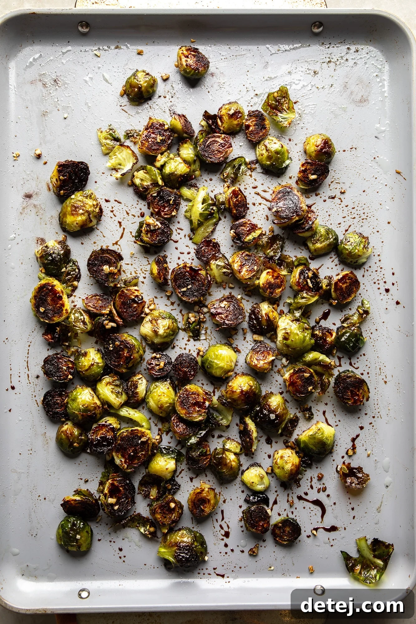 A baking sheet filled with freshly roasted Brussels sprouts, showing off their golden-brown, slightly charred edges and tender texture.