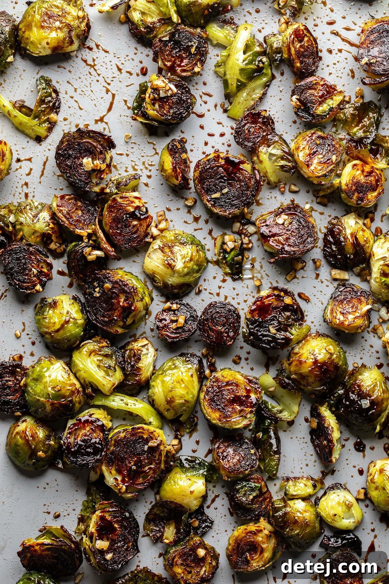A close-up shot of roasted Brussels sprouts artfully arranged on a baking sheet, showcasing their beautiful char and glossy balsamic glaze.