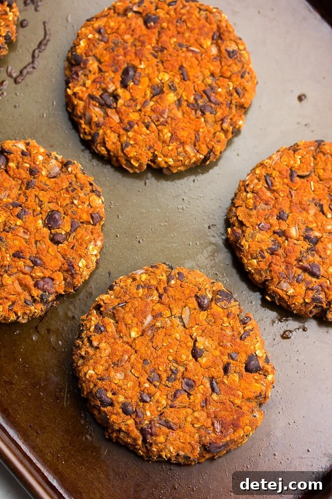 Cooked sweet potato black bean burgers, golden brown and slightly crisp, resting on a baking pan after being removed from the oven.