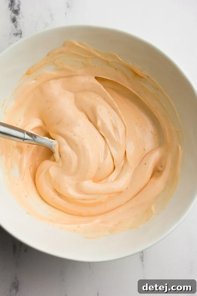 A small white bowl filled with creamy, pink Sriracha mayo, ready to be served.