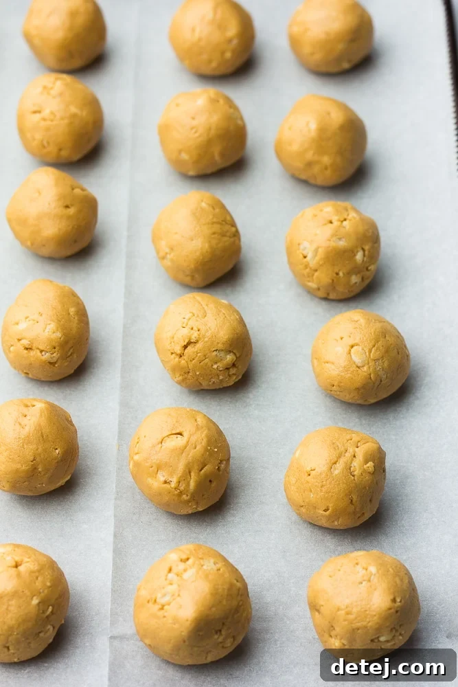 Uncoated vegan peanut butter balls resting on parchment paper on a baking sheet, ready for their chocolate bath.