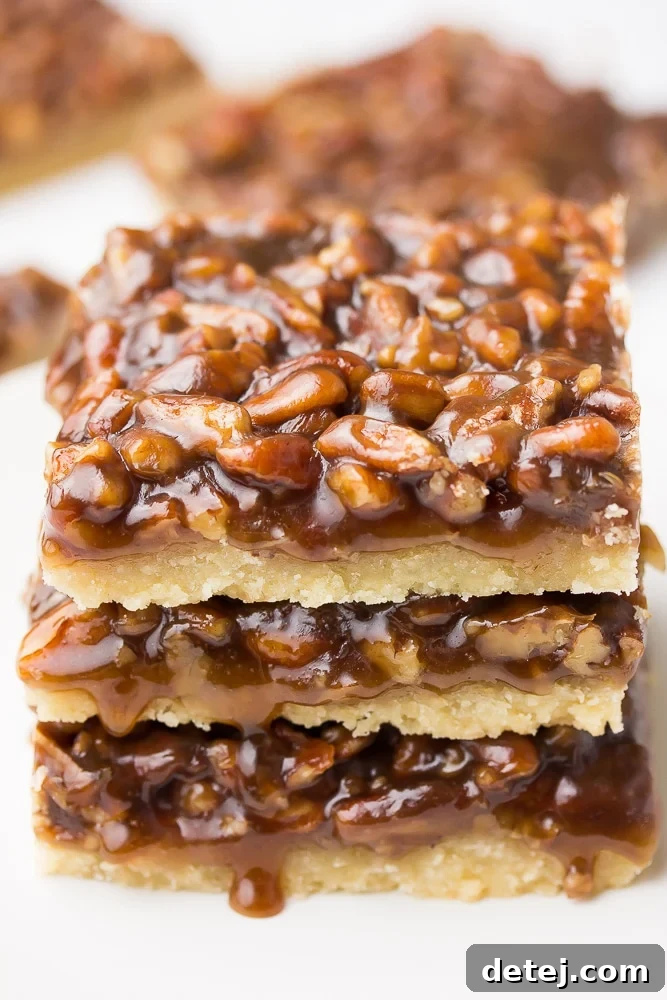 Three perfectly stacked vegan pecan bars, showcasing their golden crust and generously rich pecan topping, ready to be enjoyed.