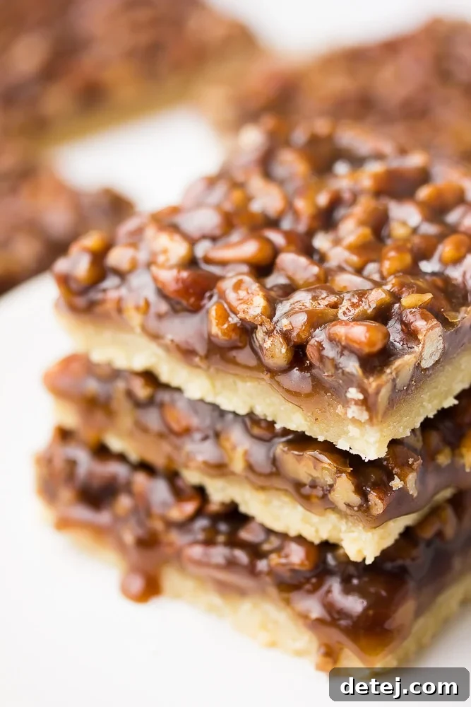 A captivating side view of perfectly stacked vegan pecan bars, highlighting the distinct layers of crust and filling.